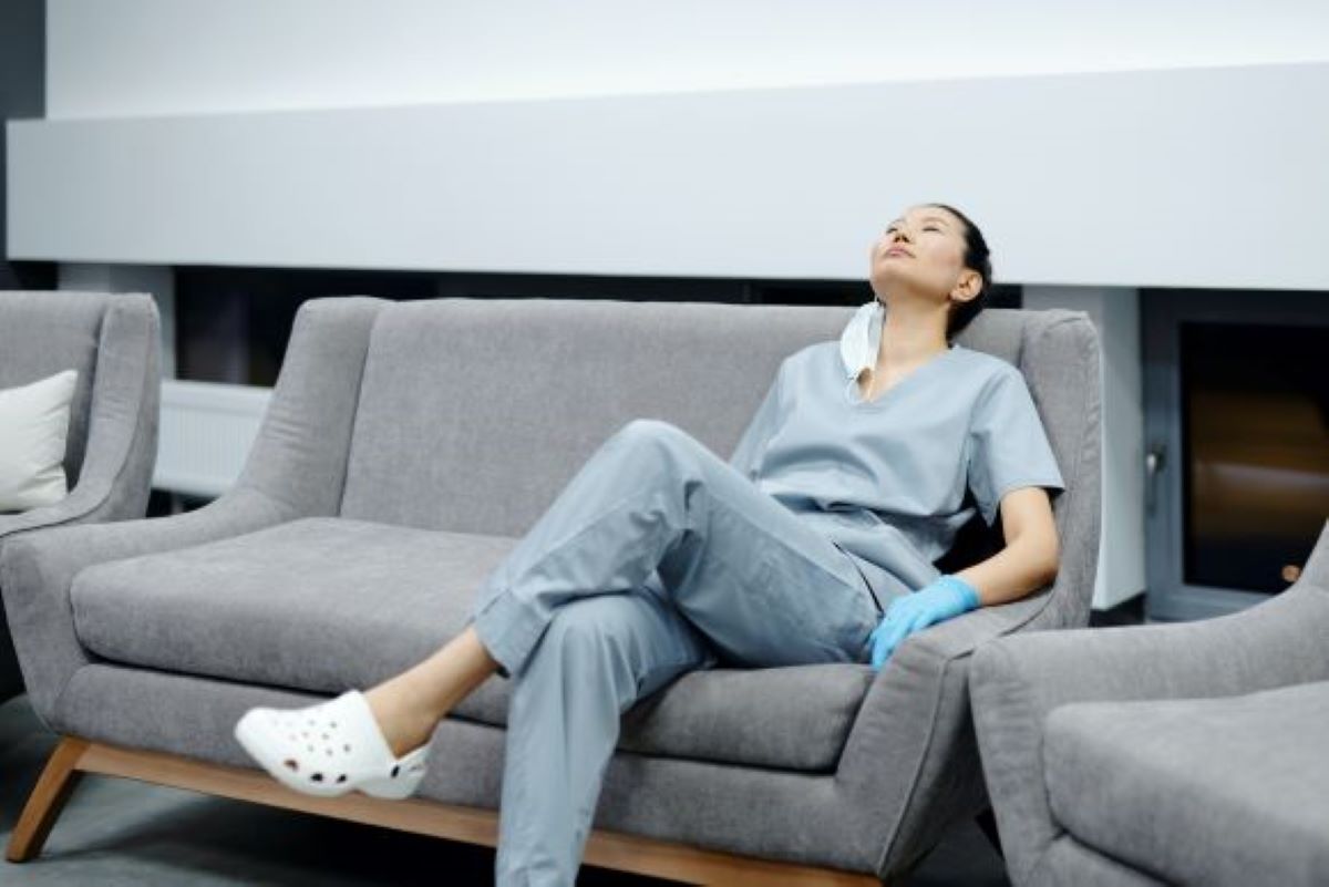 Nurse experiencing nurse burnout while sitting on a couch after a shift