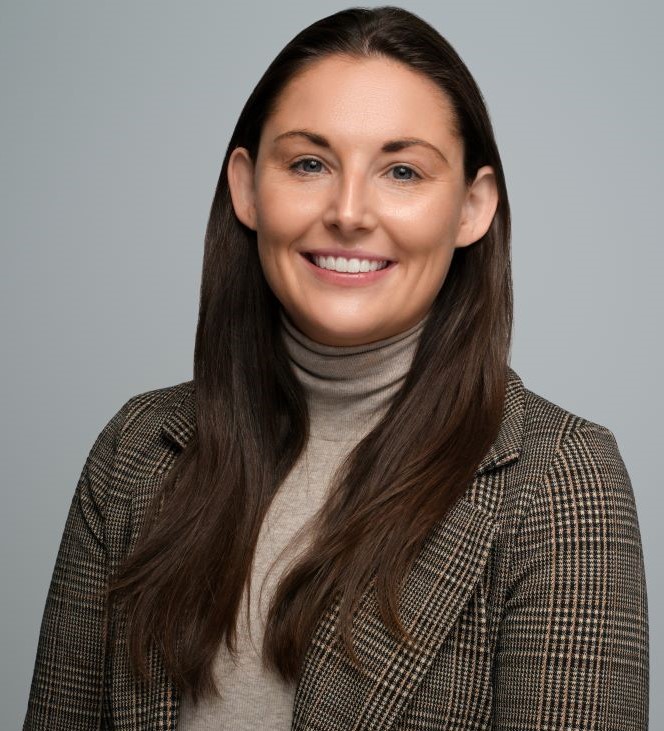 Woman with brown hair posing in front of a gray background