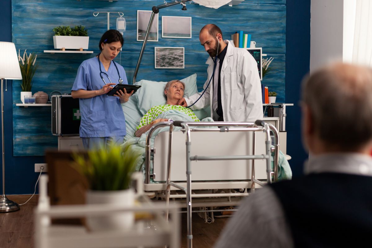 A physician and nurse check in on a nursing home patient as they prepare for their CMS certification.