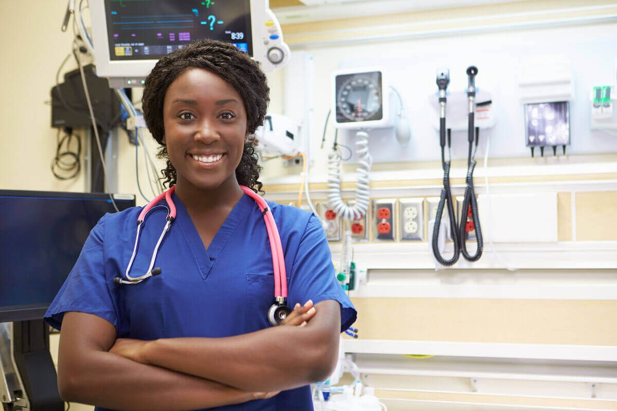 African-American nurse in blue scrubs with her arms folded in the emergency room.