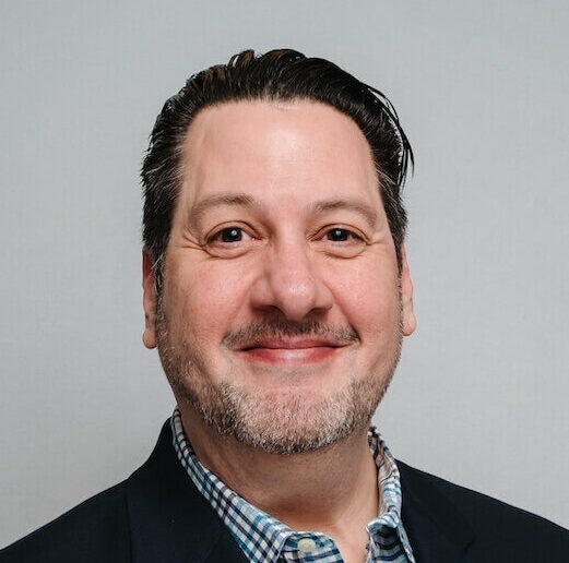 White adult man with beard and dark sport coat smiling.