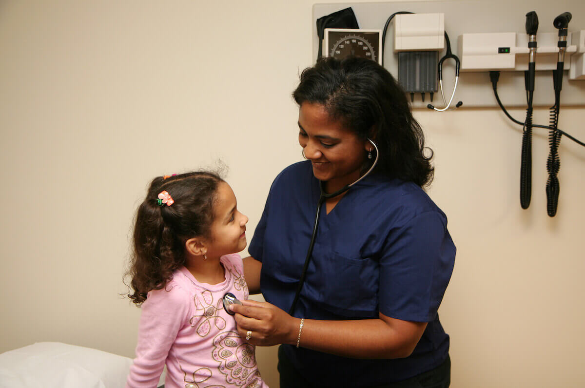 Nurse practitioner treating a young girl in an office.