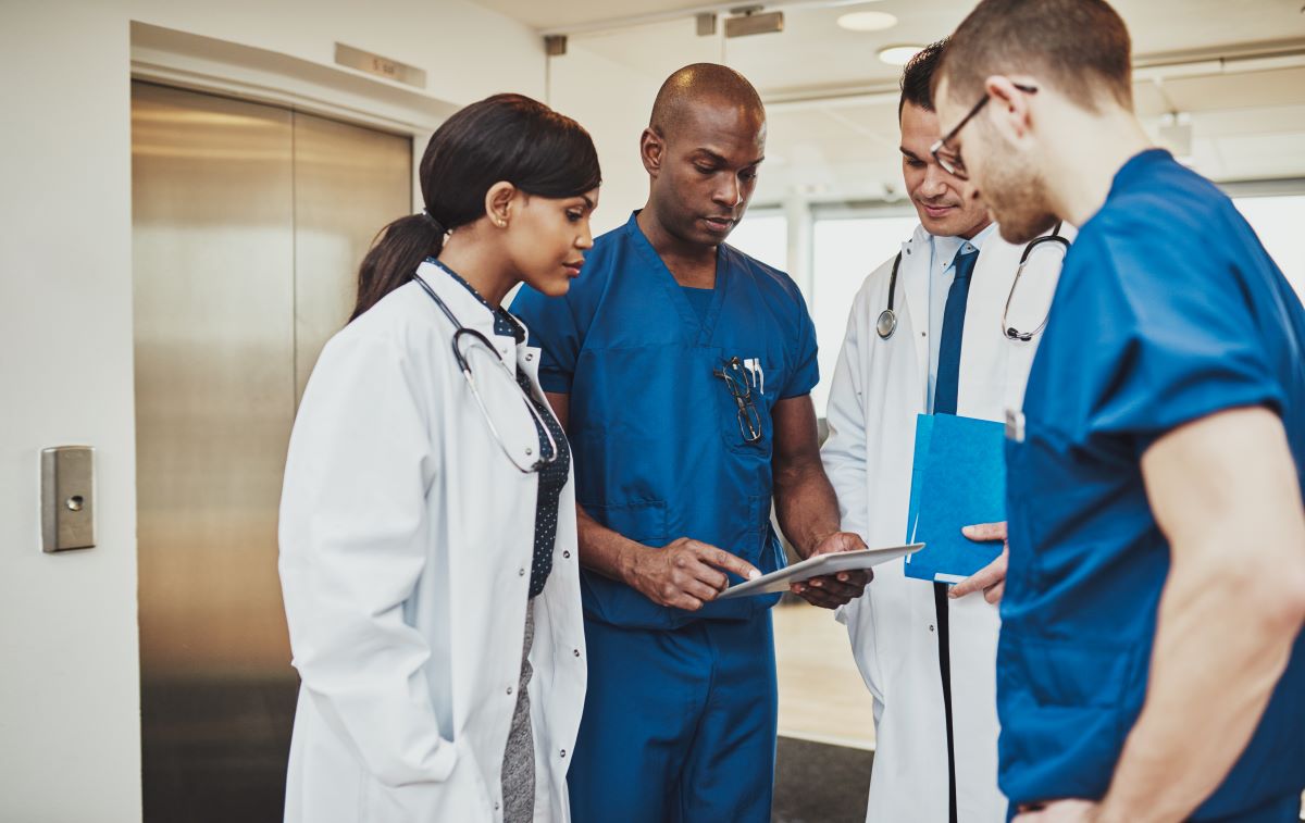 Nurses meeting with physicians in a healthcare facility's hallway.