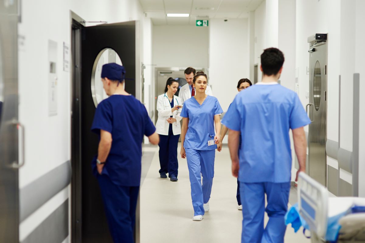 A hospital hallway, with nurses and other medical staff walking.