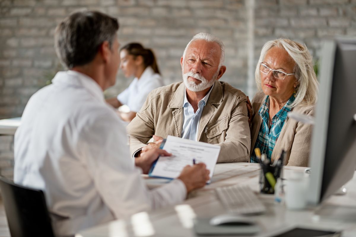 A medical administrator discusses Medicare reimbursement rates with an older couple.