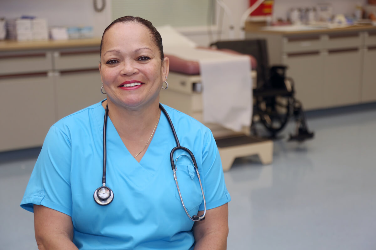 African American per diem travel nurse sitting and smiling.