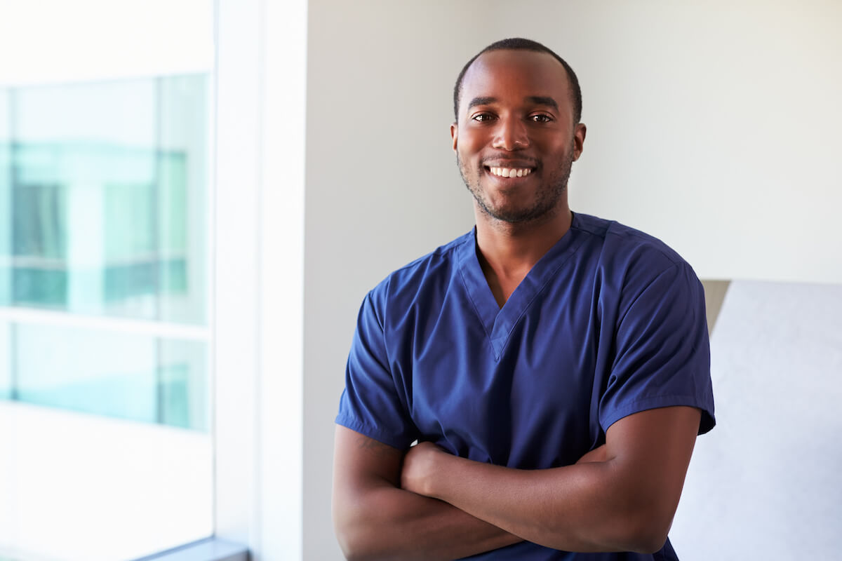 African American male nurse crossing arms and smiling after completing the Virginia nursing license renewal process.