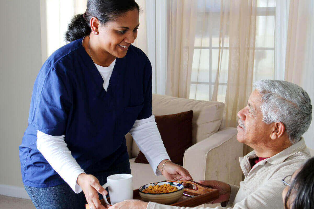 SRNA brings a meal to a senior patient.