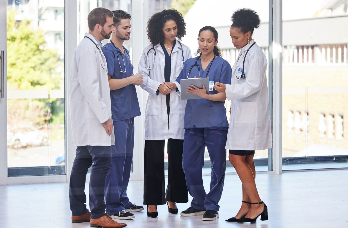 Five nurses looking at the schedule for the current shift.