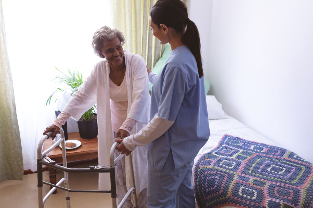 A nurse meets with a nursing home resident in her room.