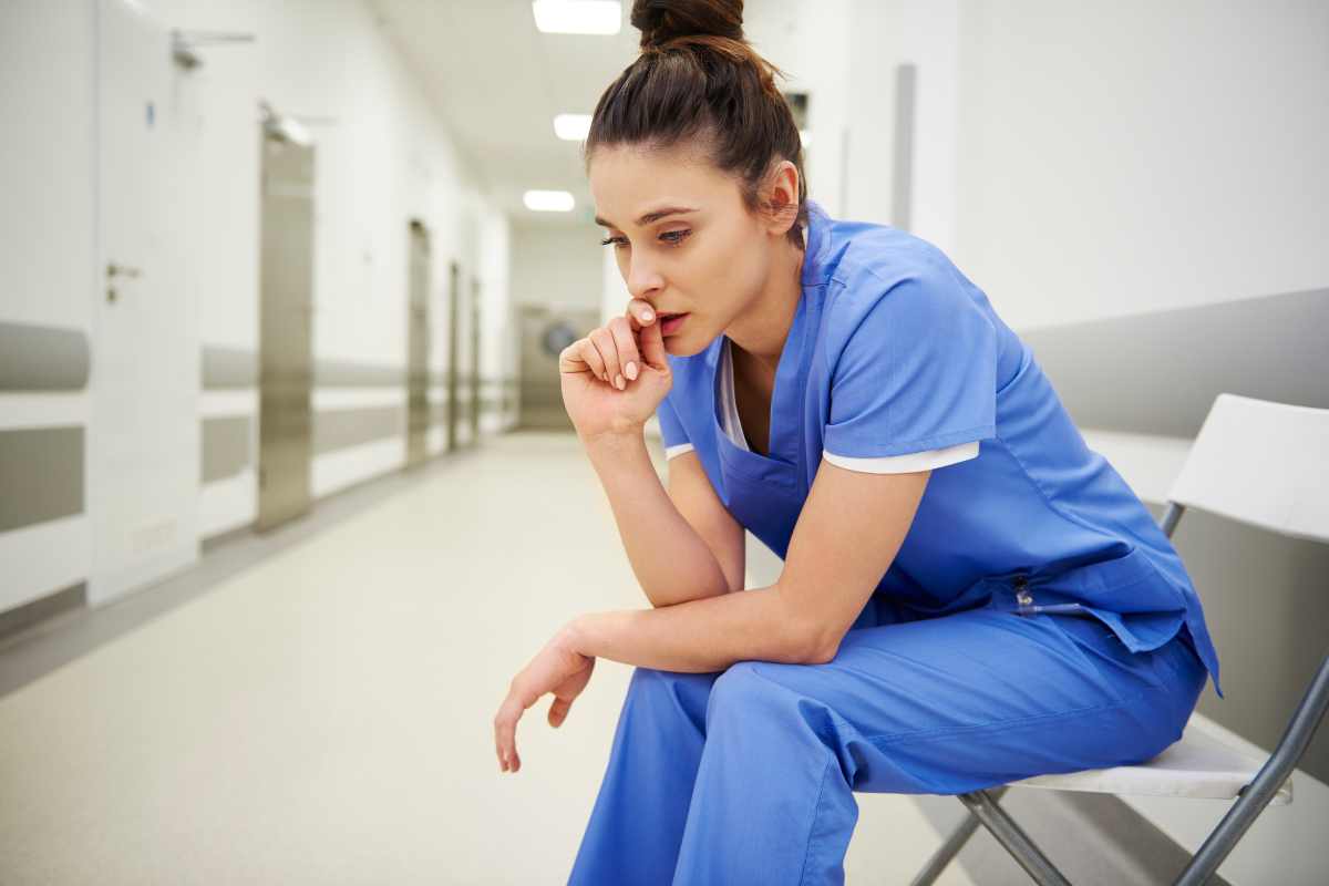 Nurse with pre-shift anxiety sitting in a chair and bitting her thumb nail.