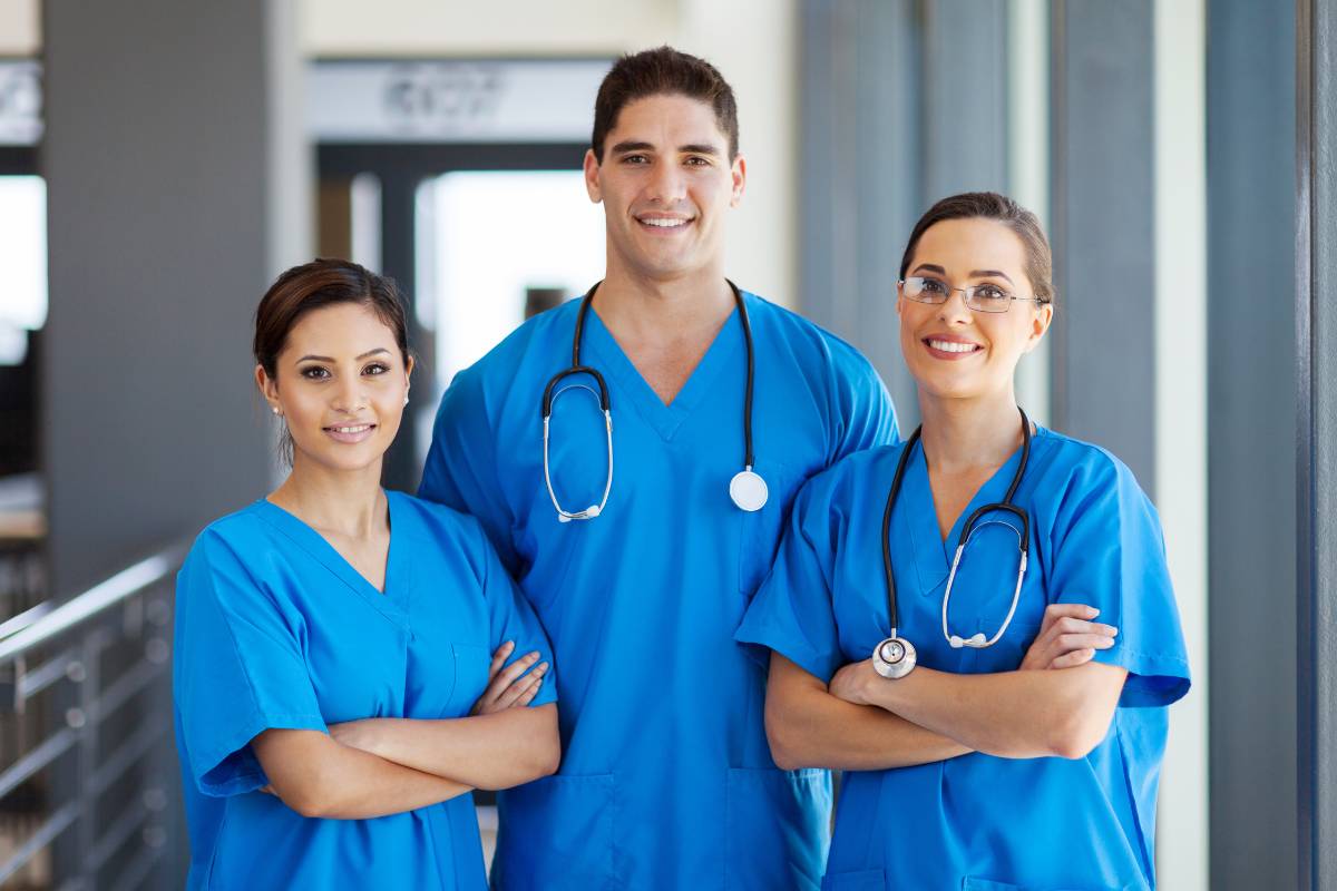 A group of nurses in blue scrubs demonstrates the ANA Code of Ethics for nurses.