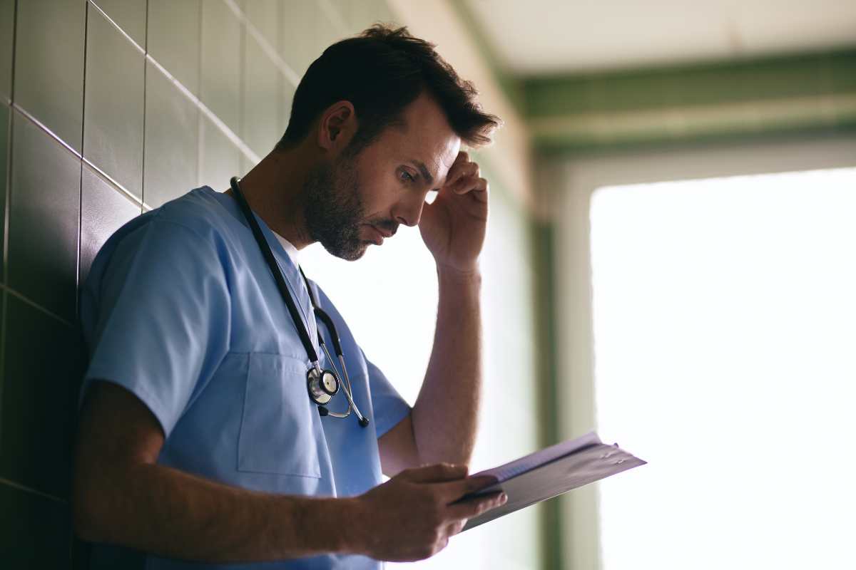 Male nurse reading a paper on how to avoid losing a nursing license.