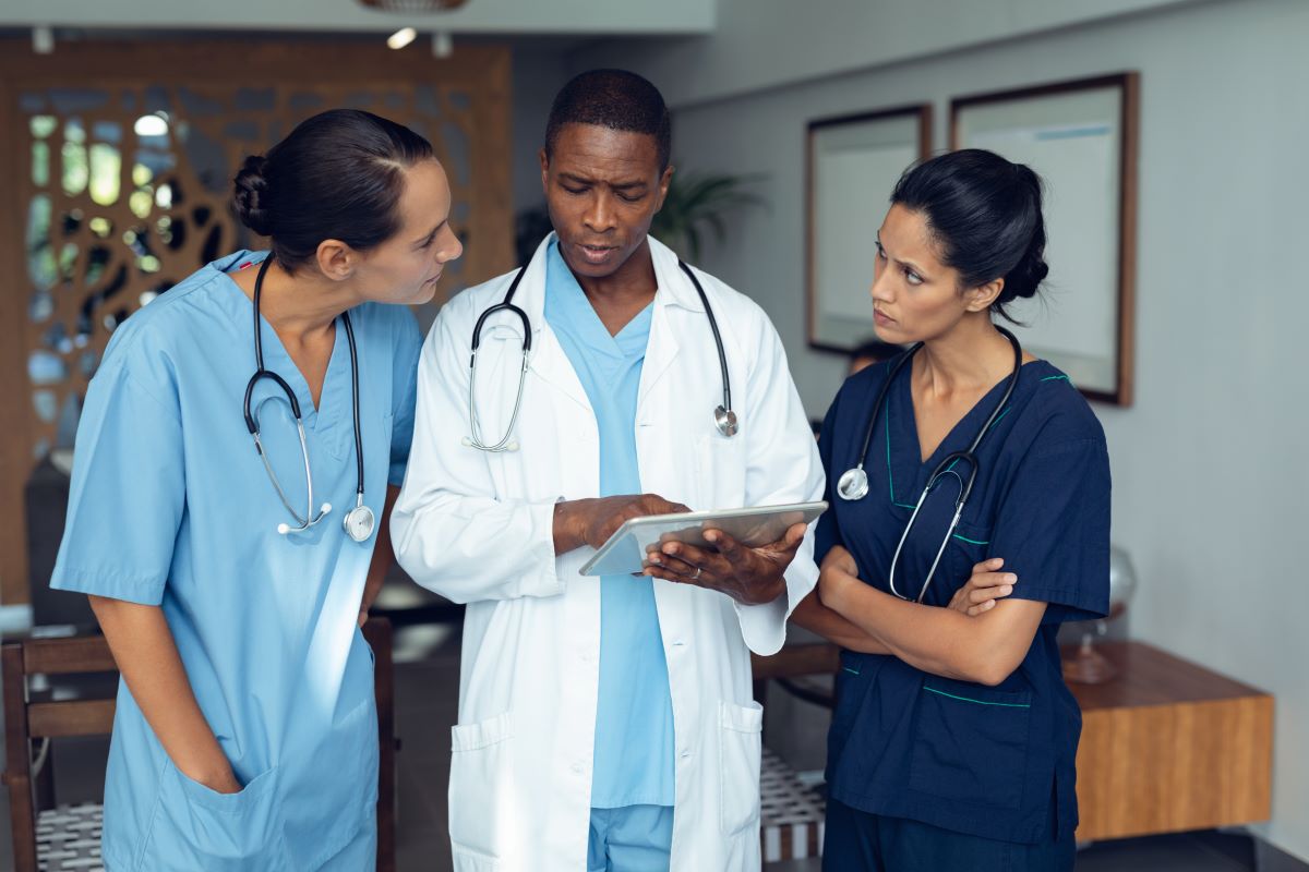 A doctor goes over patient files with two nurses.