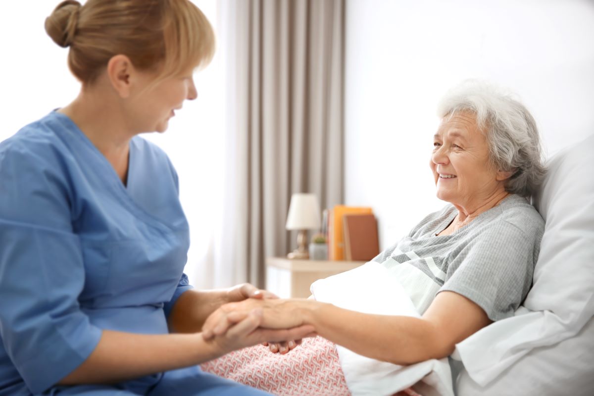 Nurse holding the hand of a patient in a nursing facility