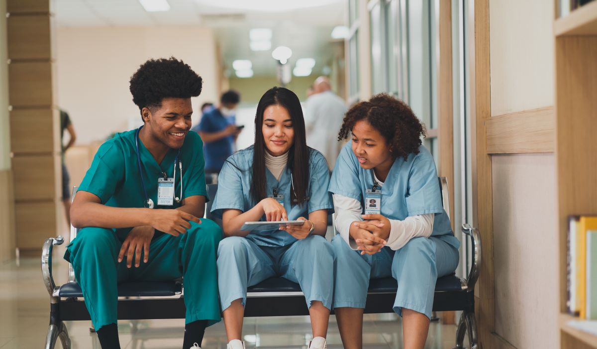 Three nurses sitting on a bench and talking to one another