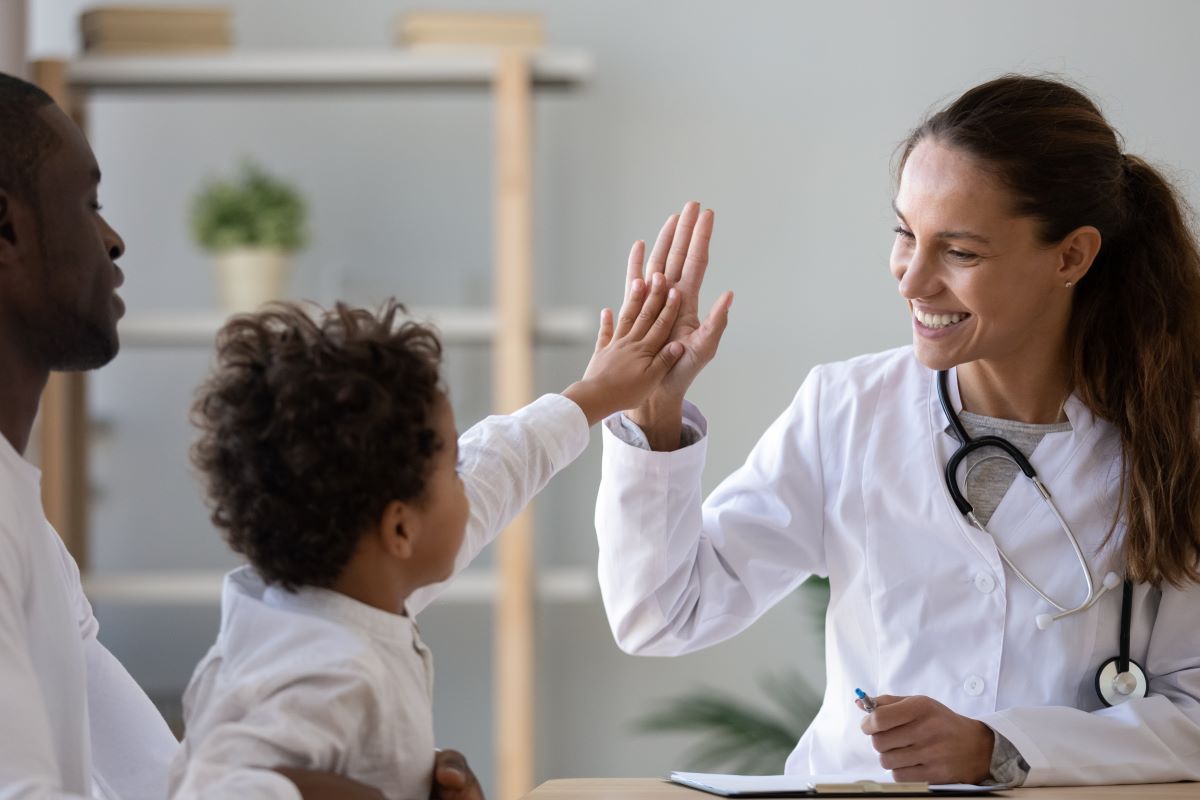 A doctor high-fives a young patient.