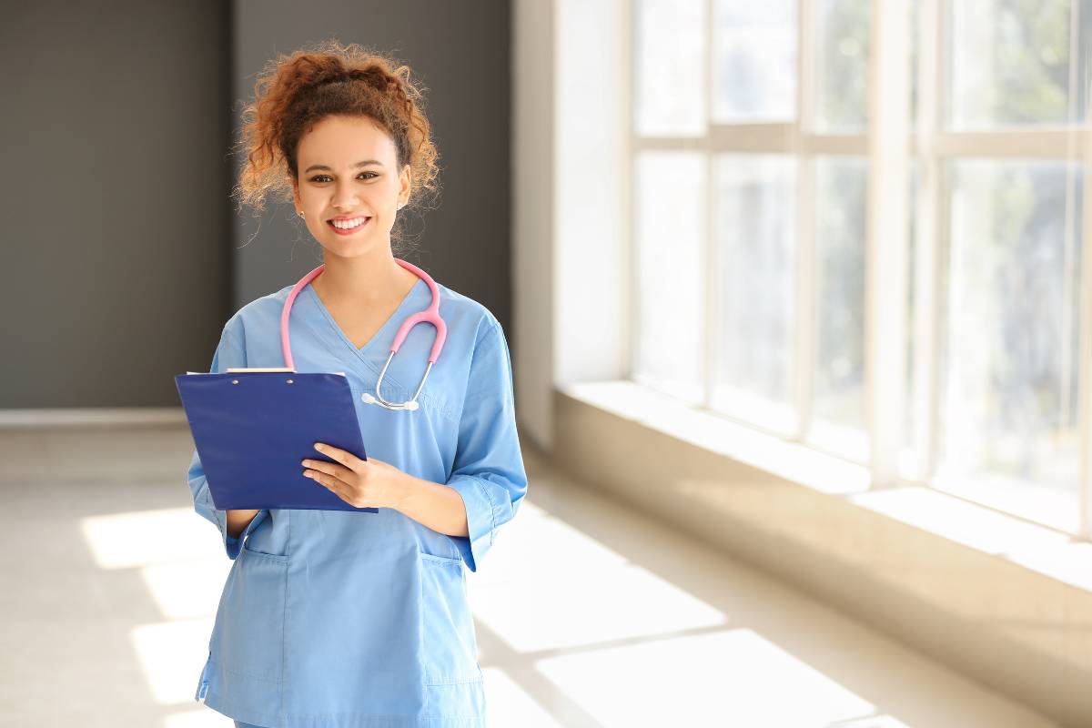 A nurse in blue scrubs works on her certified medical assistant resume.