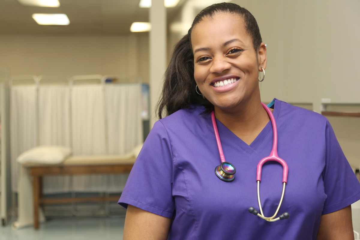 African-American nurse in purple scrubs who completed the New York nursing license renewal process.