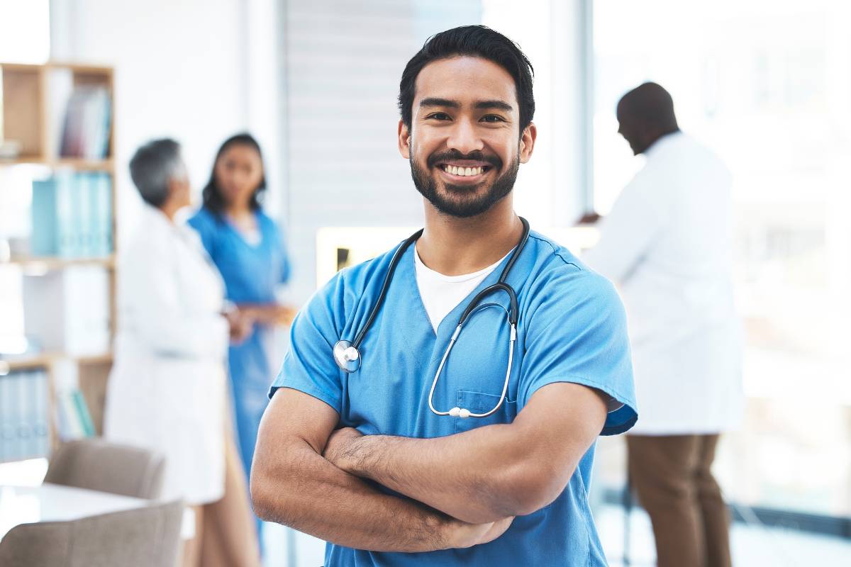 A CVICU nurse smiles and crosses his arms.