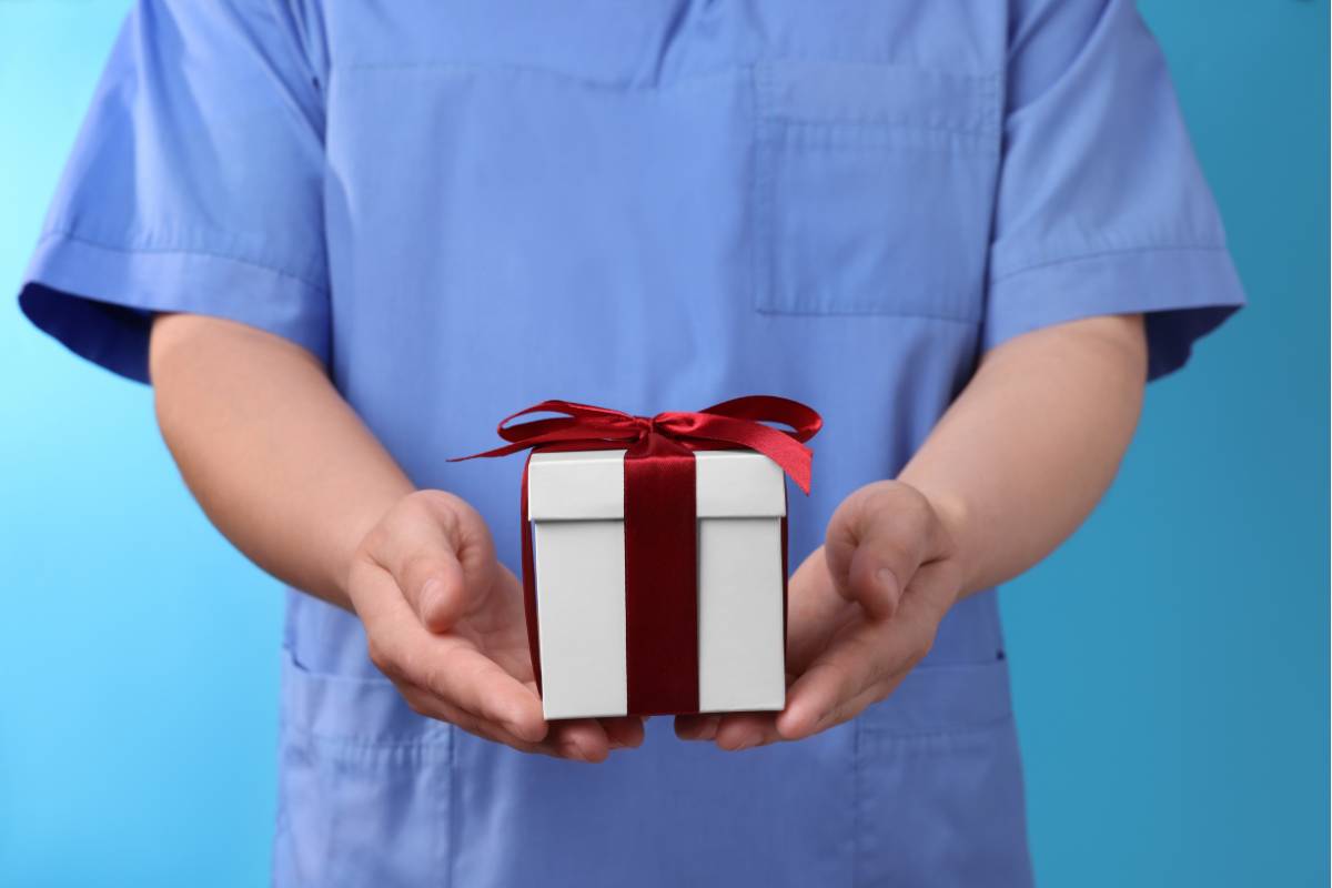 A nurse in blue scrubs holds one of their nurse retirement gifts.