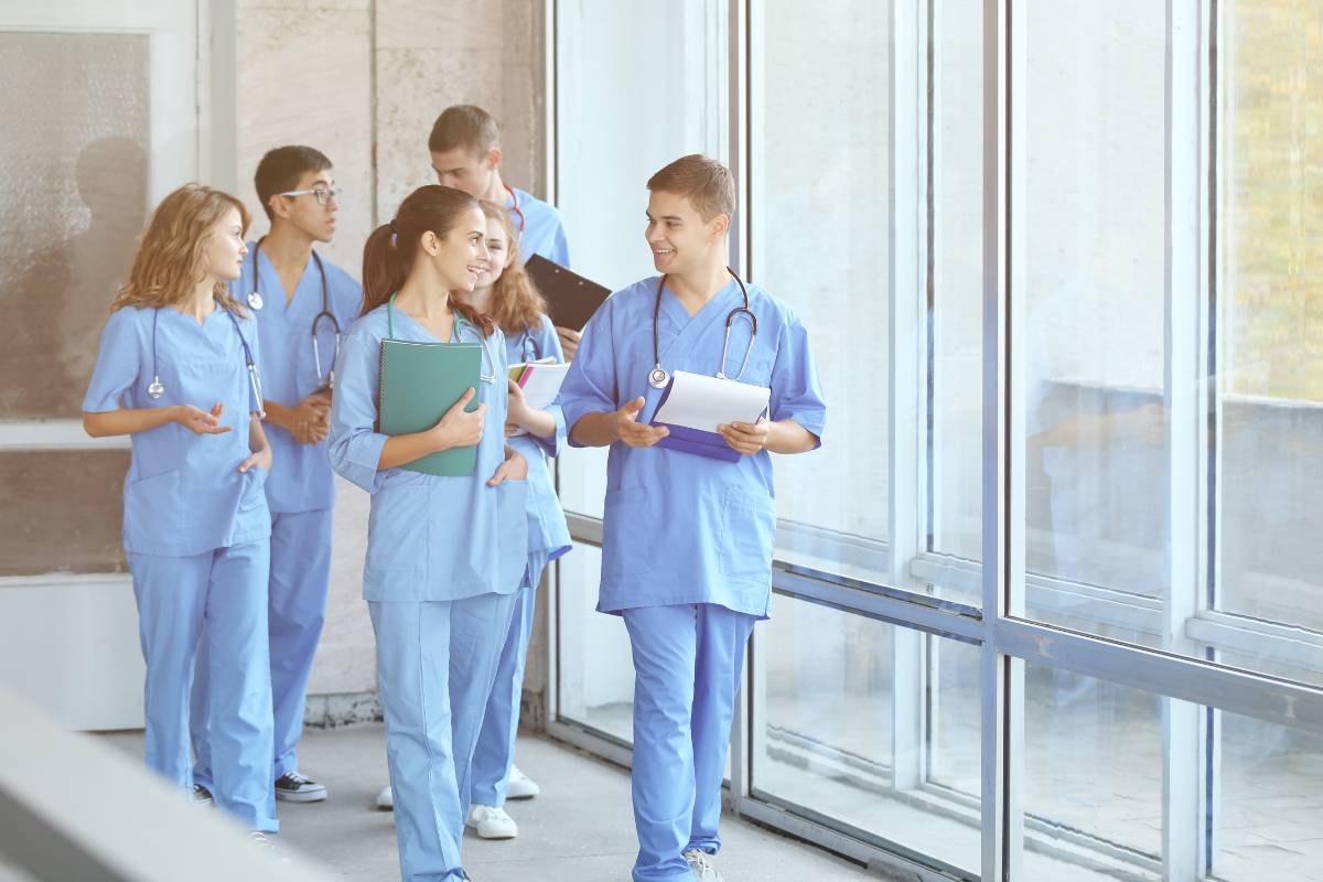 A nursing student talks to his friends in the hallway.