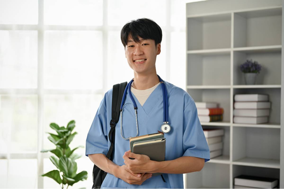 A nurse holds a stack of nursing books.