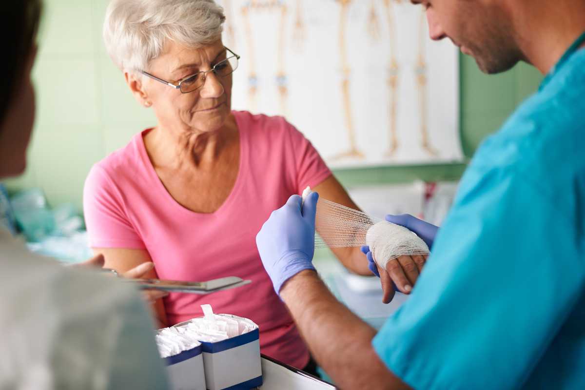 Wound care nurse wrapping a woman's hand with a bandage.