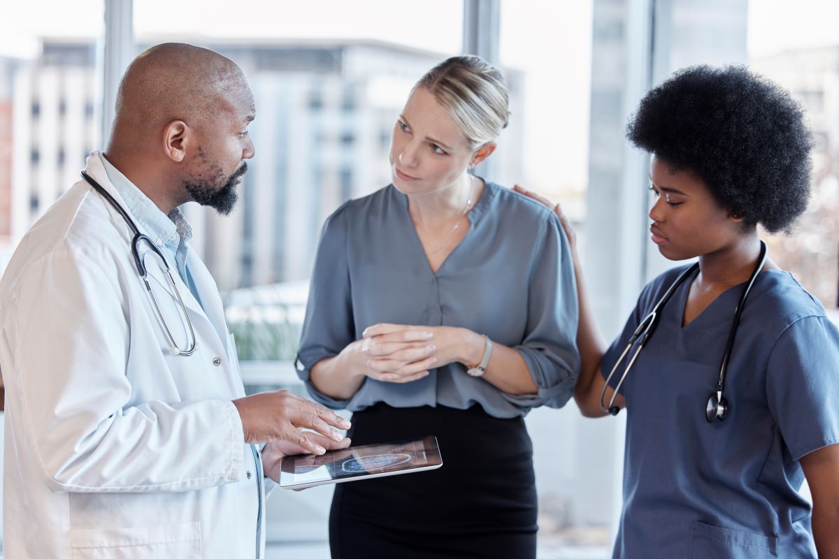 A healthcare facility manager meets with a physician and a nurse.