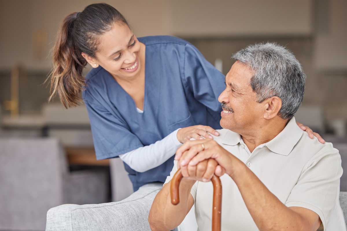Home health aide in New York greeting resident on a couch.