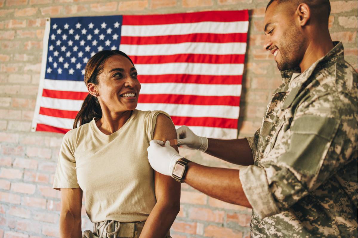 A military nurse gives another service member a shot.