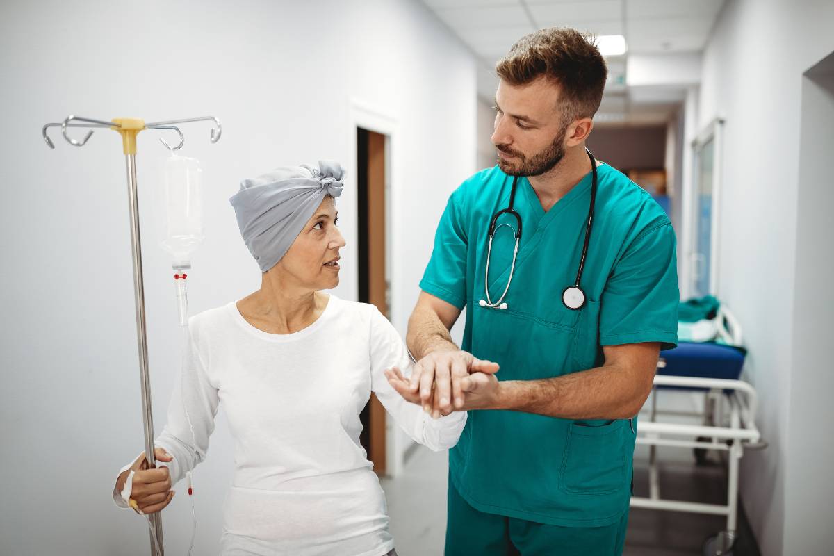 A nurse uses his skills from chemo certification to assist a patient.