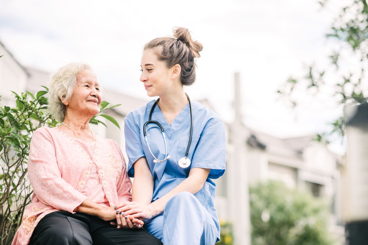 A nurse sits and has a conversation with an elderly patient.