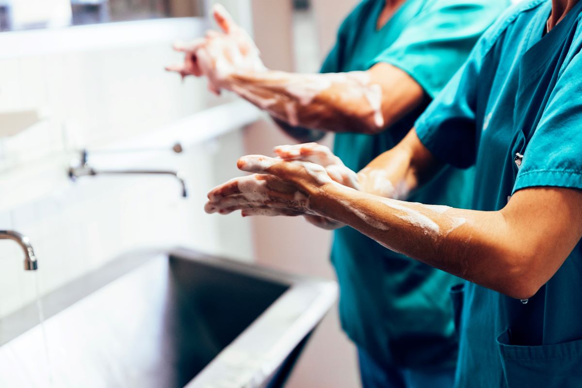 A nurse demonstrates proper hand hygiene by washing her hands after visiting a patient.