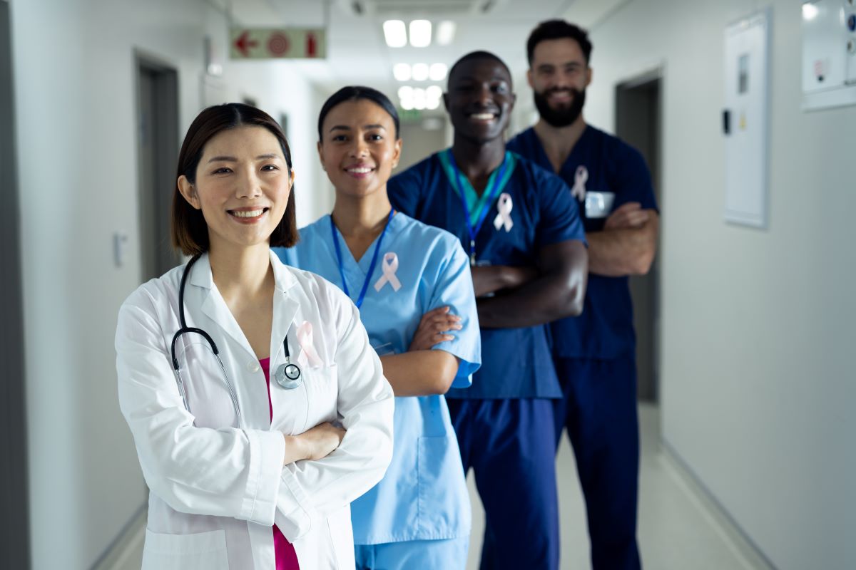 A physician and three of her nurses stand in the hallway, smiling, with their arms crossed.