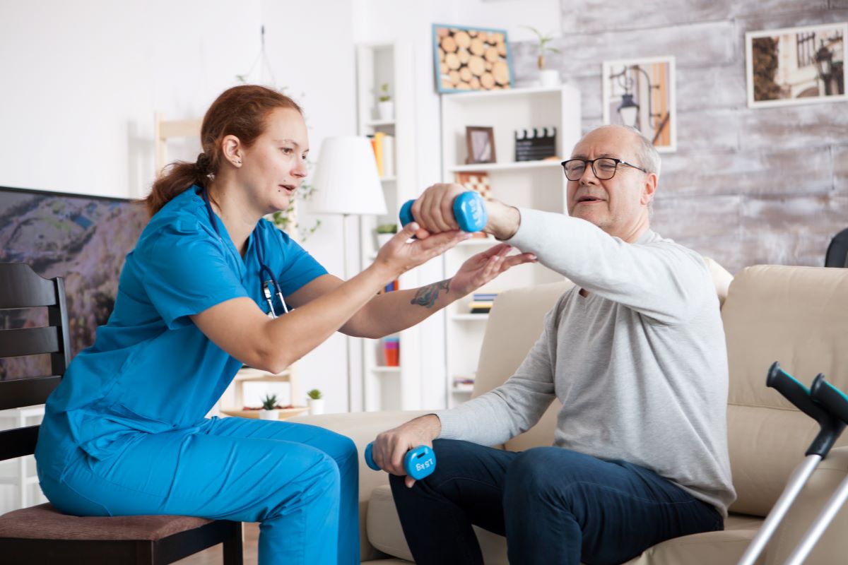 A nurse helps a nursing home resident with his daily exercises.