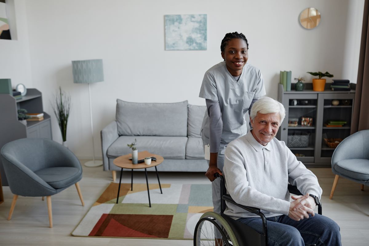 A nurse helps a resident, in a wheelchair, move around.