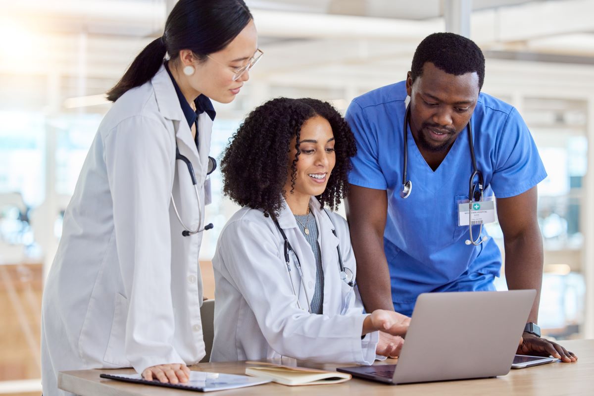 Healthcare professionals gather around a laptop computer and discuss their content marketing strategy.