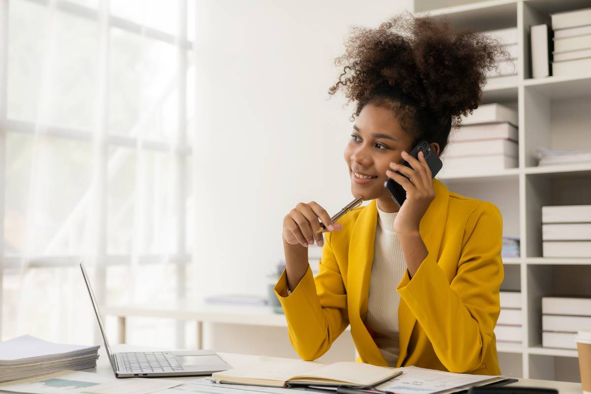 A nurse entrepreneur sits at a desk on a business call.