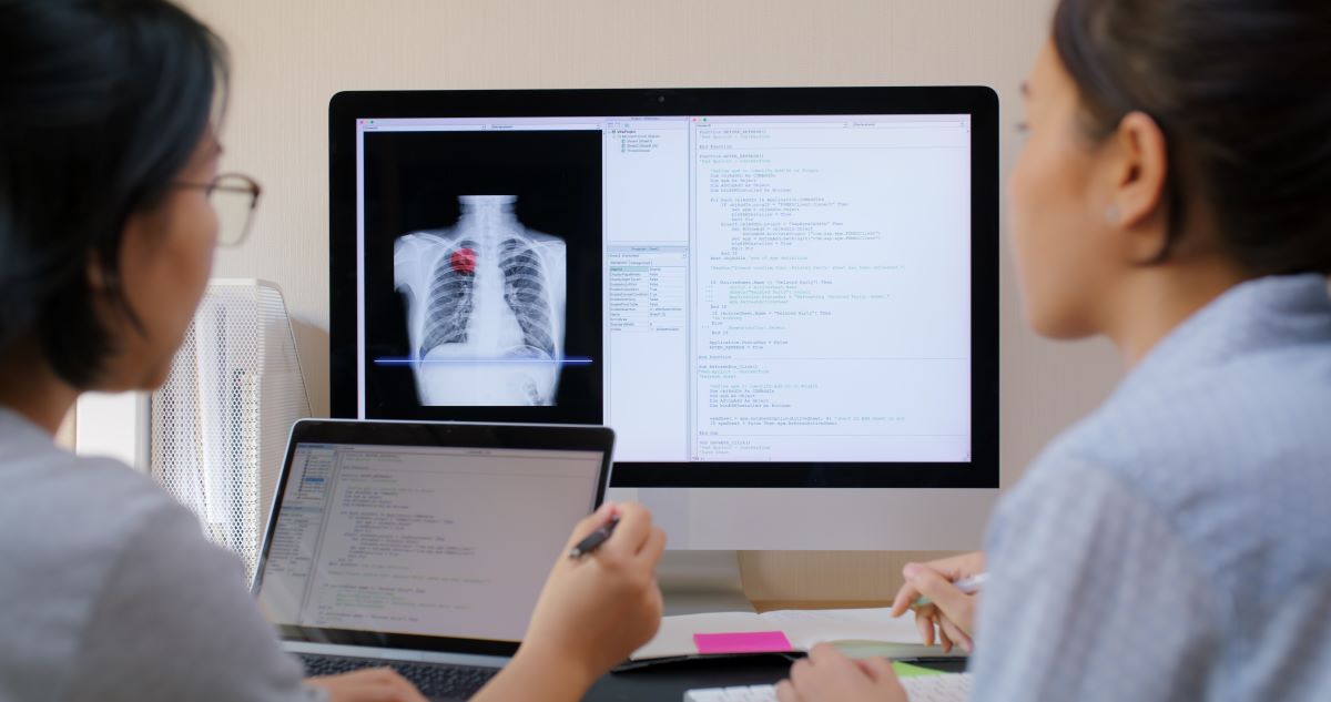 Health informatics professionals look at data on a screen.