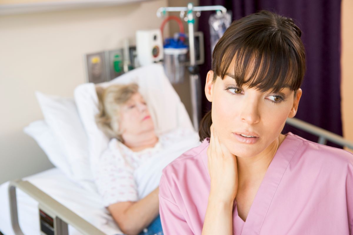 A fatigued nurse standing near one of her patients.