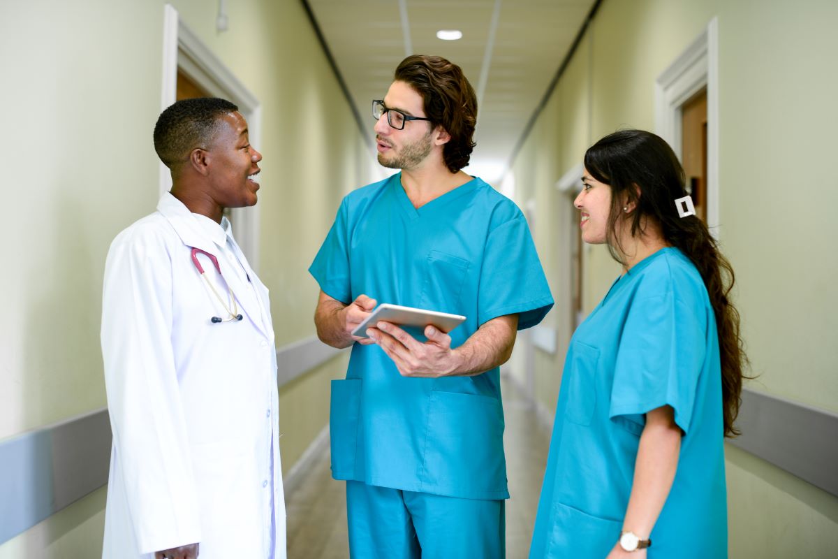 Nurses meet with their supervising physician in the hallway of a hospital.