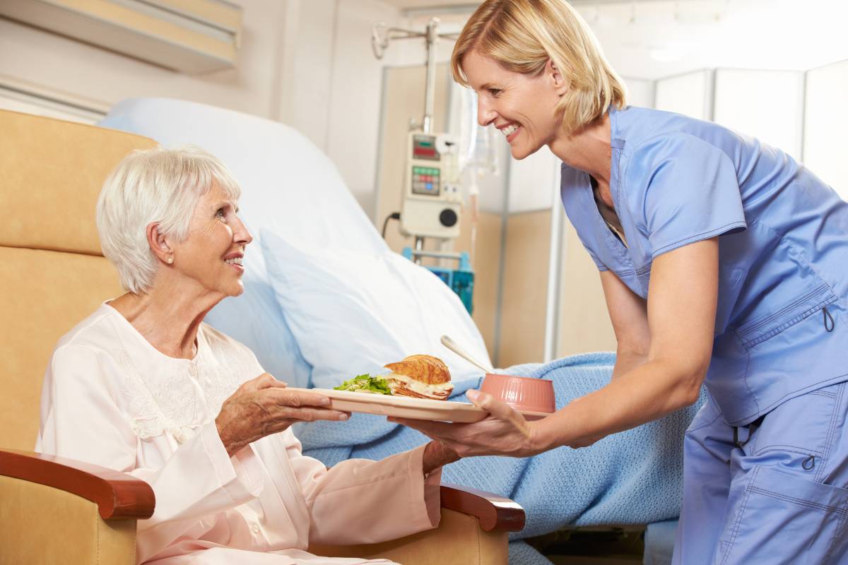 A nutrition nurse hands a patient their meal.