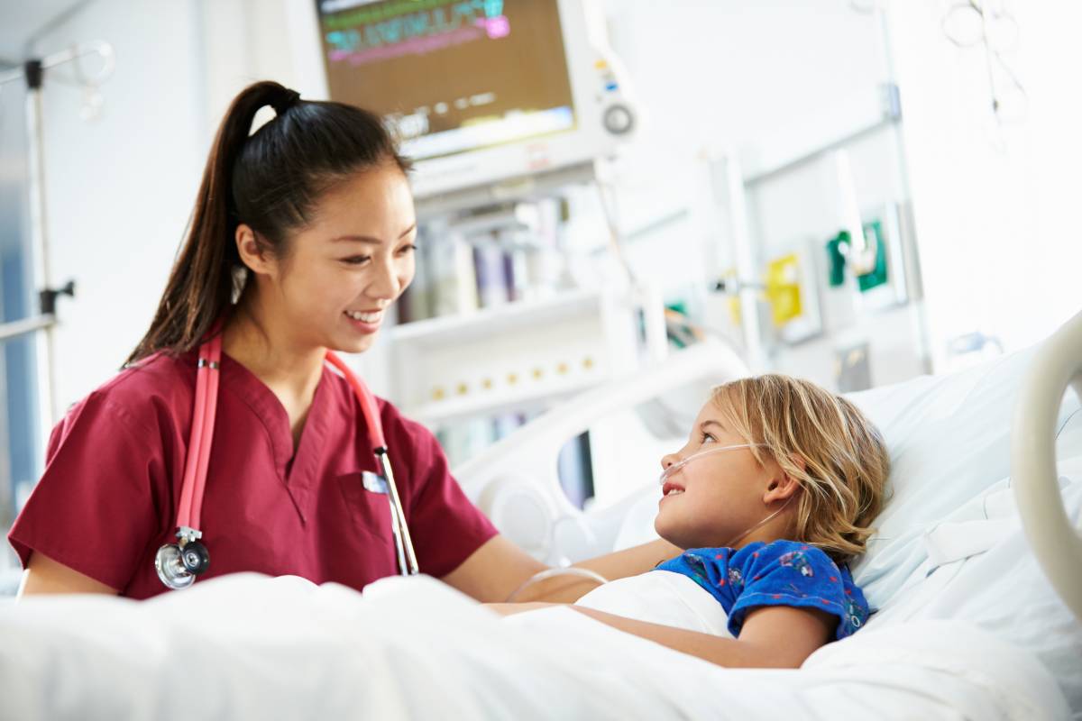A student nurse works with a young patient while deciding between PICU vs. NICU nursing.