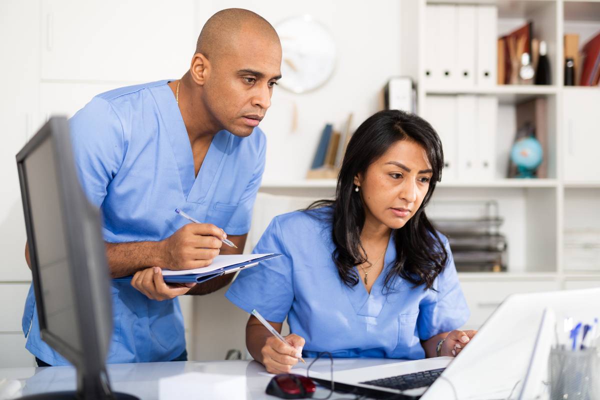 Two nurses practice time management in nursing as they plan their shift.