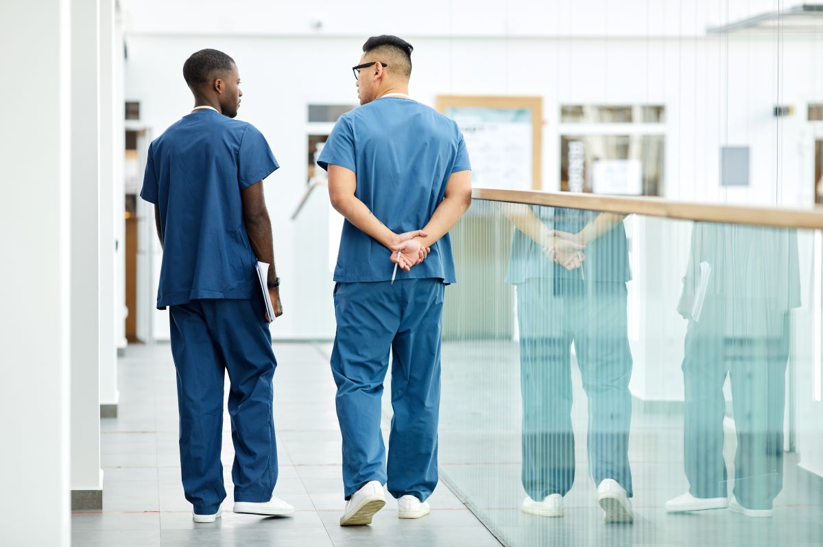 Two nurses walk down the hall and talk.