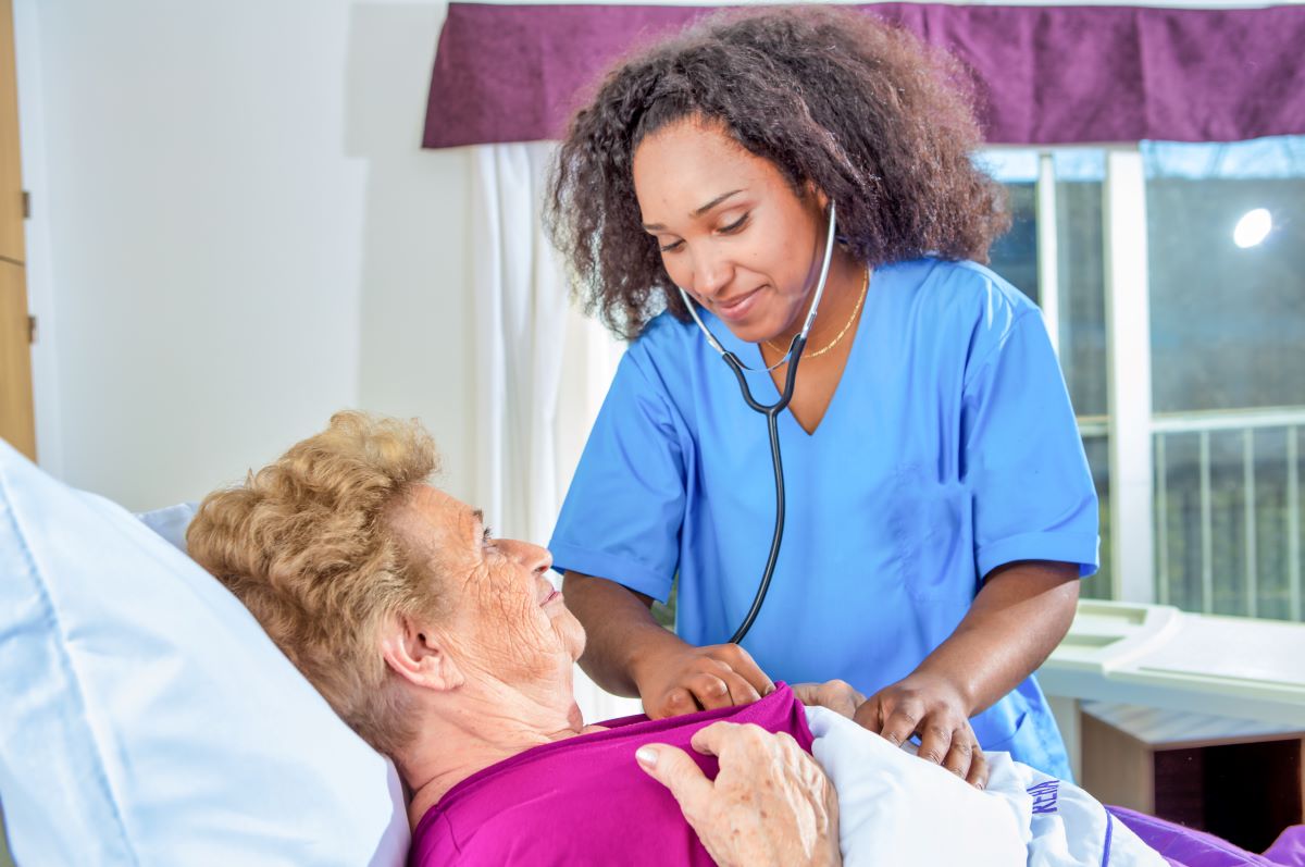 A nurse attends to a patient in her room.
