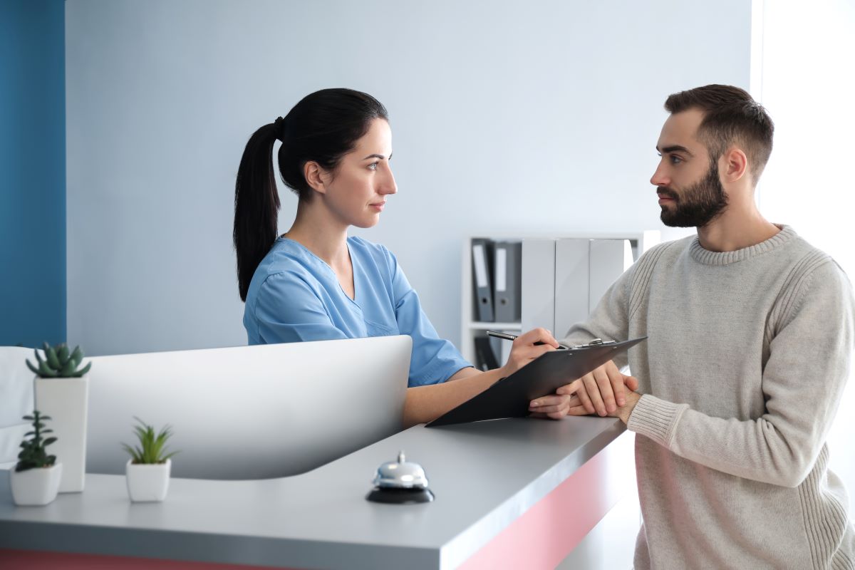 A receptionist at a hospital goes over the treatment plan and billing with a patient.