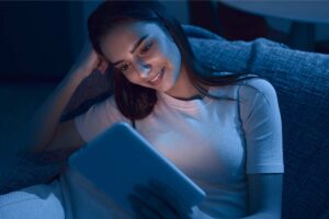 Young woman reading from a tablet in low light.