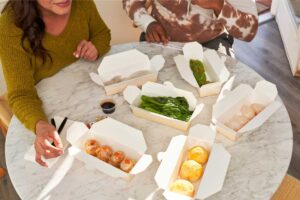 Two people enjoying takeout from containers.
